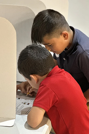 Student helps a younger student with voting